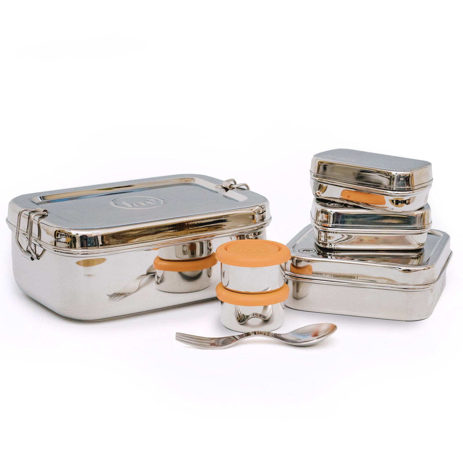 A set of stainless steel food containers including an Elephant Box 2 litre lunch box, small dressing pots with silicone lids, and a spork, all displayed on a white surface.