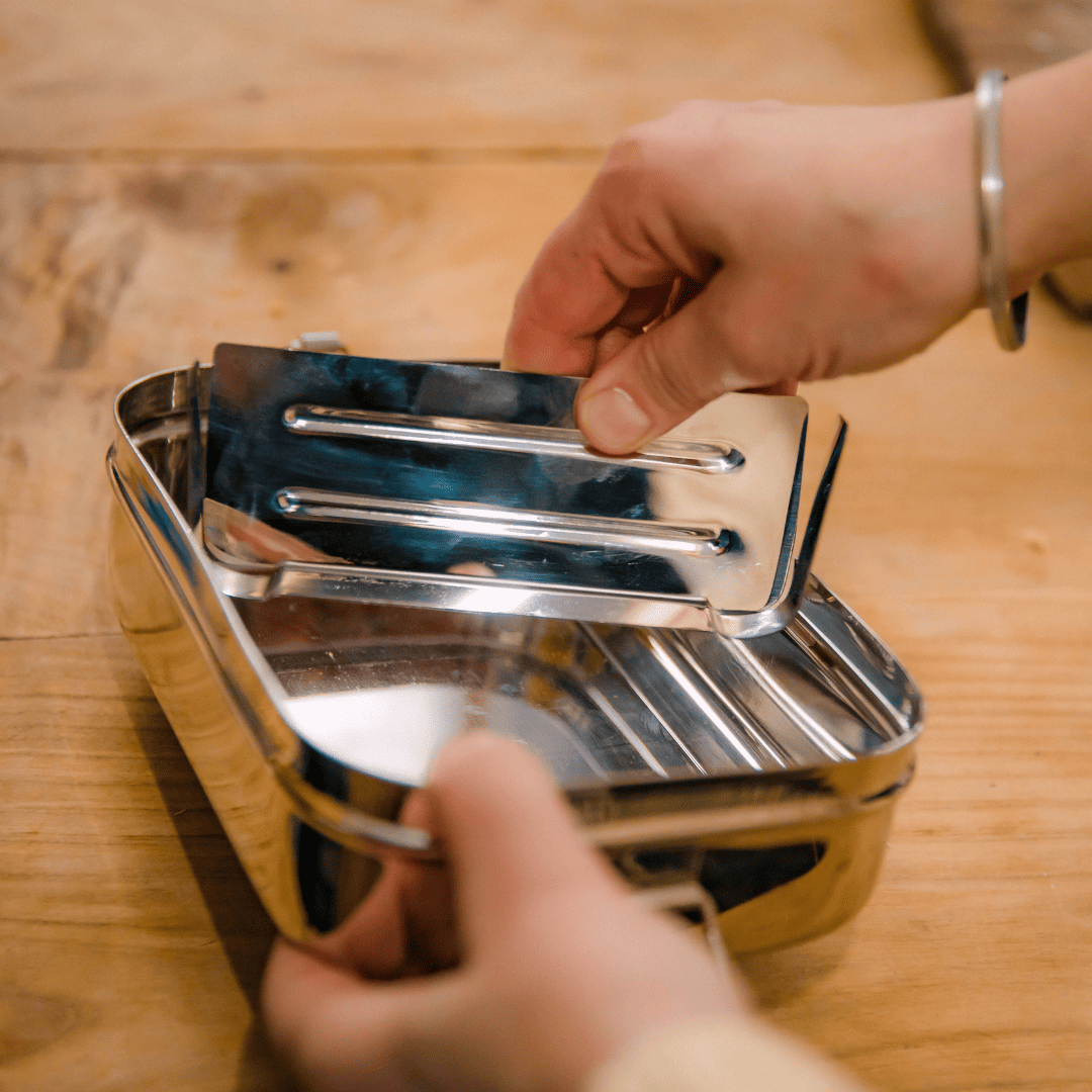 Picture shows the removable divider that it's possible to buy for the Jumbo 2 in 1 lunchbox or the Original Elephant Box 2ltr. The divider is made from stainless steel. the picture shows the divider being put into the lunchbox