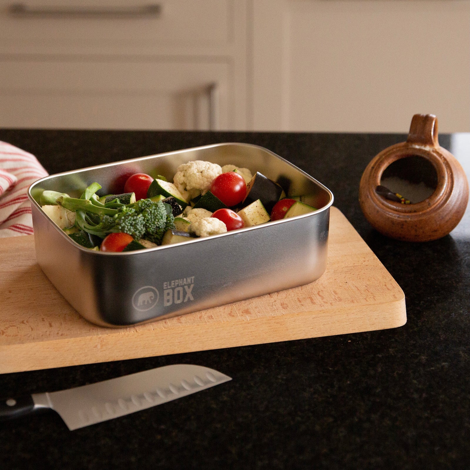 Stainless steel food container with raw veg on a kitchen counter, featuring the Elephant Box brand.