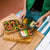 A set of three Elephant Box stainless steel  food storage containers with borosilicate glass lids, stacked from largest to smallest. The leakproof silicone vacuum seal and tab is orange in colour