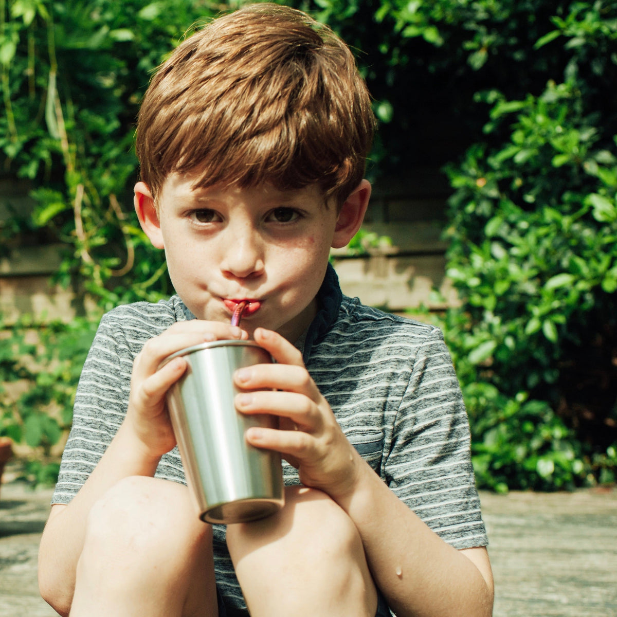 a boy drinking from a stainless steel tumbler