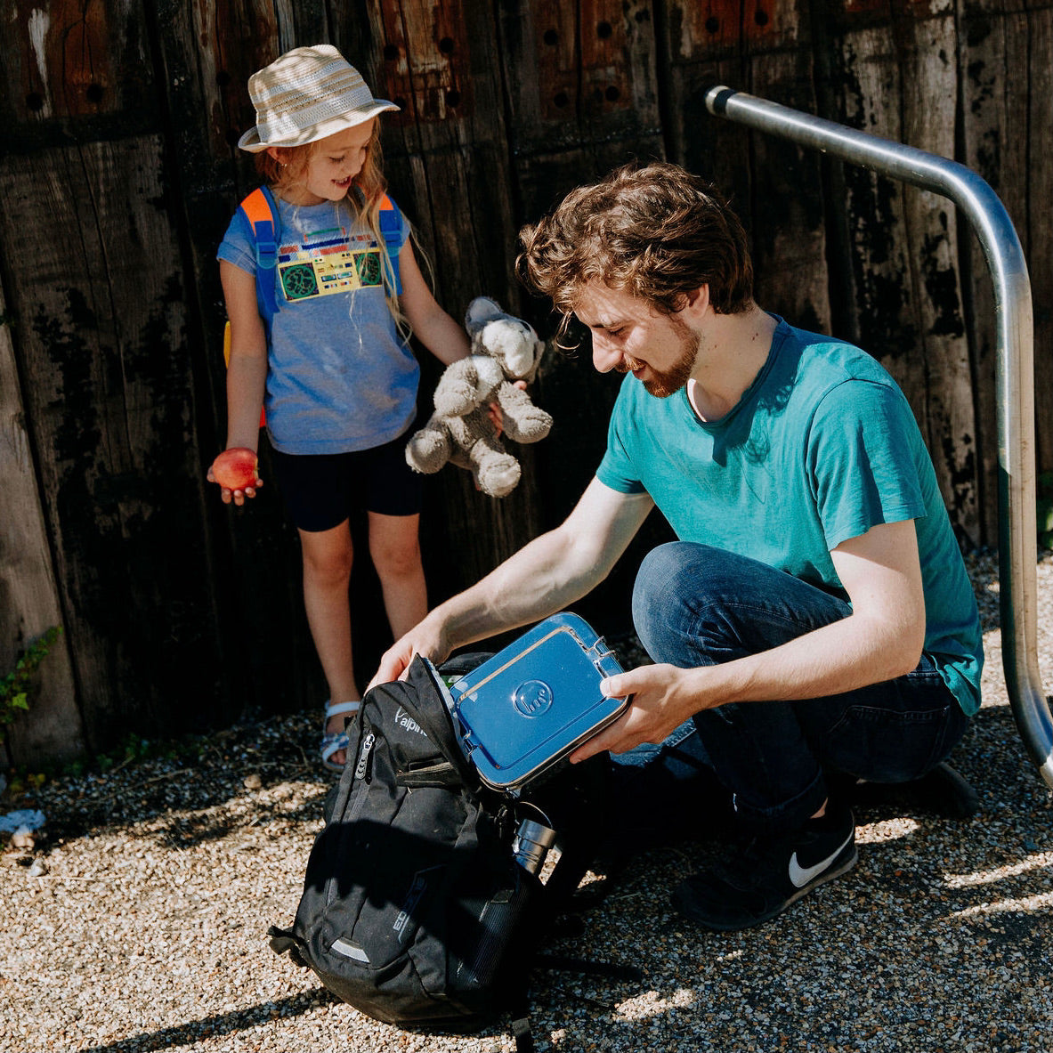 Man and child with her school lunchbox. putting the stainless steel Elephant Box into a rucksack. 